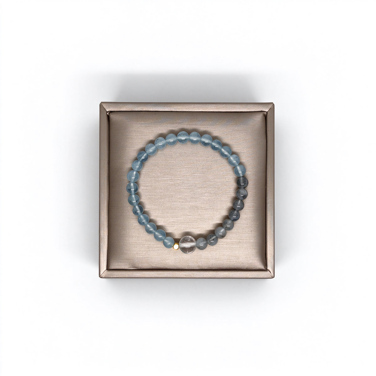 Top-down view of Serenity aquamarine bracelet on gold satin jewelry display