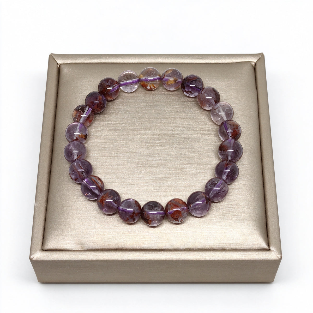 8mm purple phantom quartz stretch bracelet displayed on elegant gold satin cushion