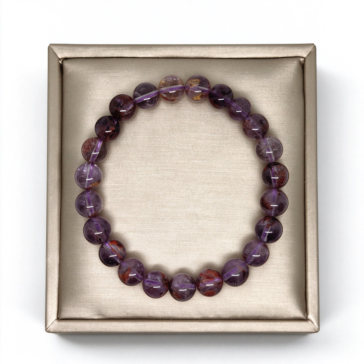 Top view of genuine purple phantom quartz beaded bracelet on square satin display base