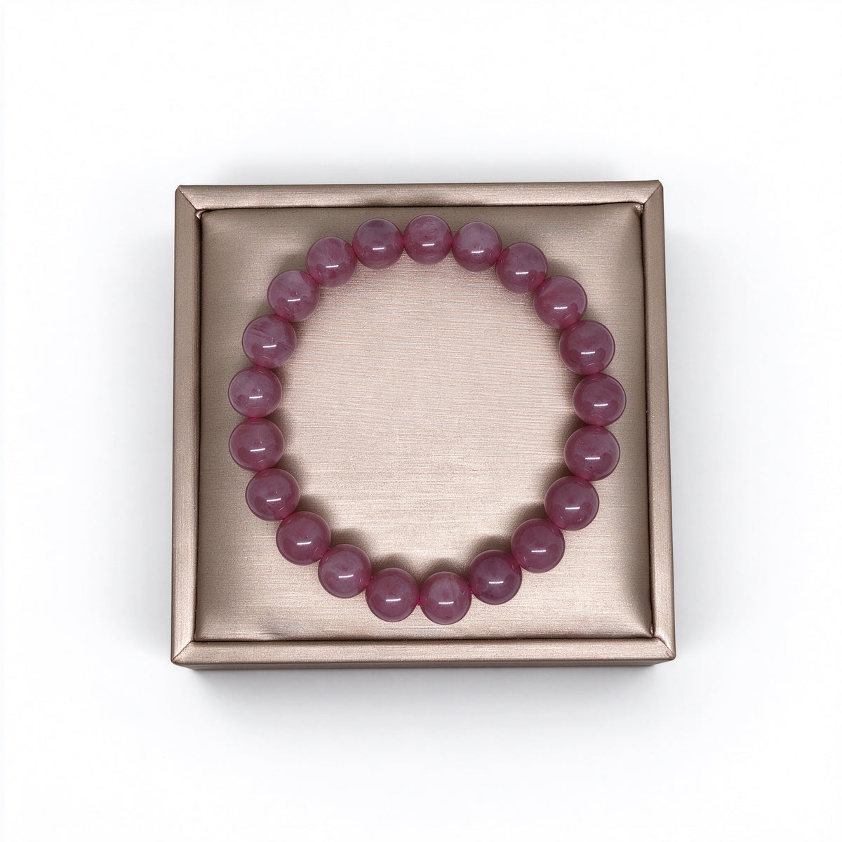 Top-down view of Madagascar rose quartz bracelet on gold satin jewelry display