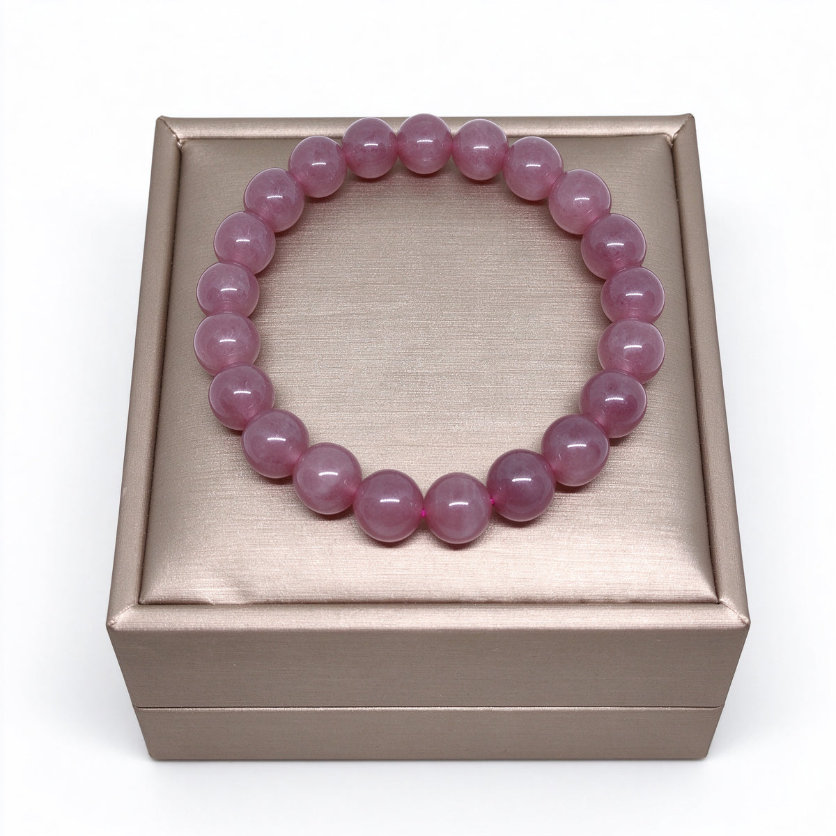 Natural rose quartz beaded bracelet resting on champagne gold jewelry stand