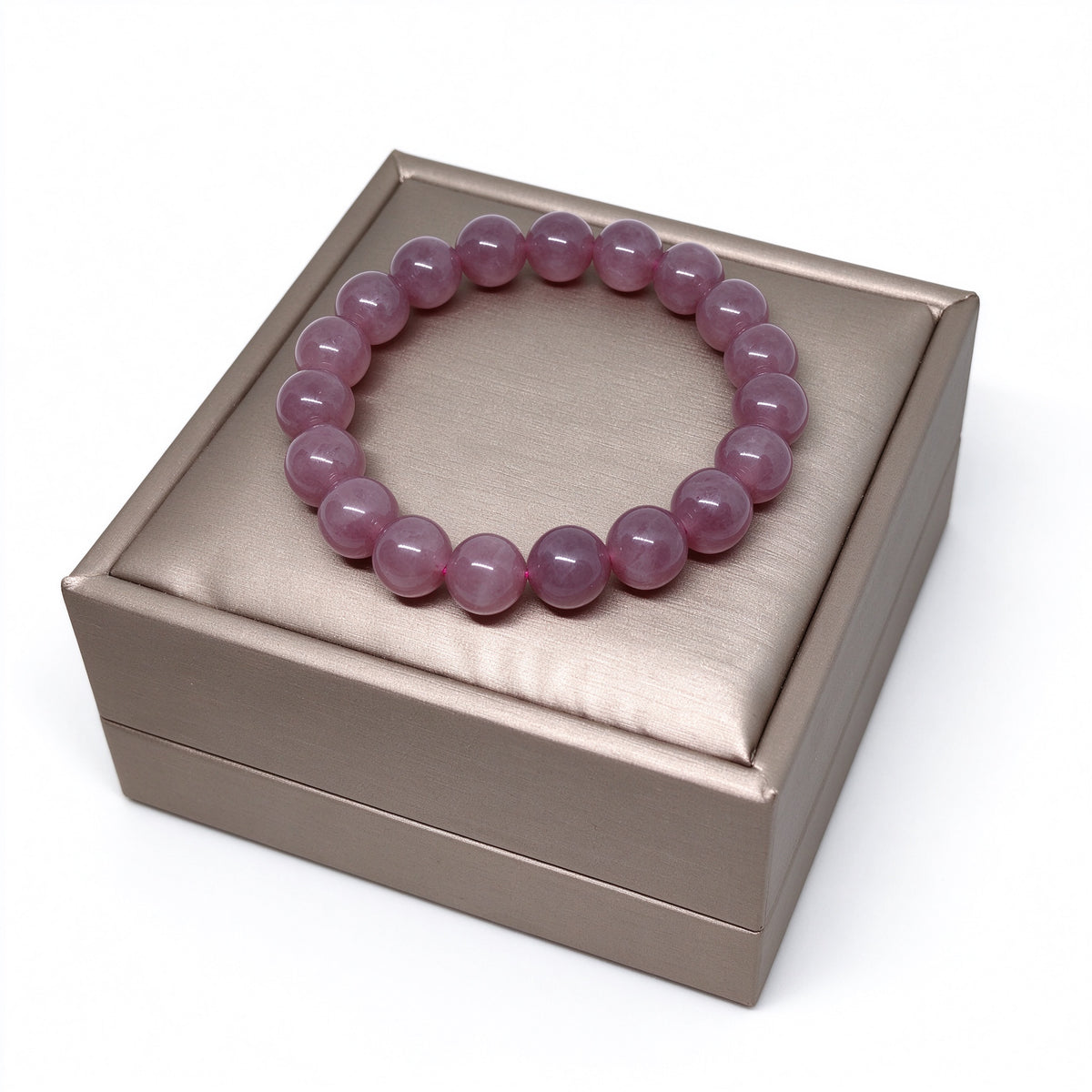 Angled view of 8mm Madagascar rose quartz stretch bracelet on gold display box